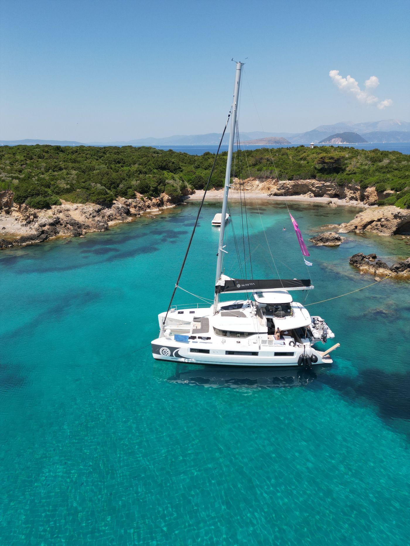Catamaran at anchor with drying sail — drone
